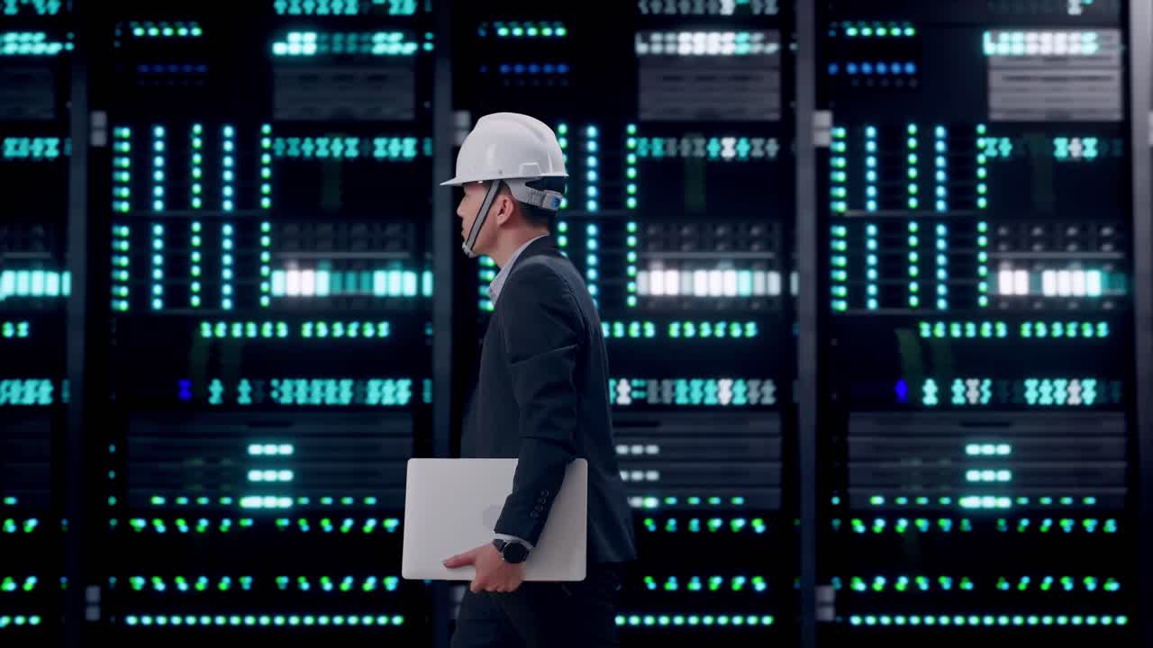 Side View of Asian Businessman Holding Computer While Walking in Server Room Data Center