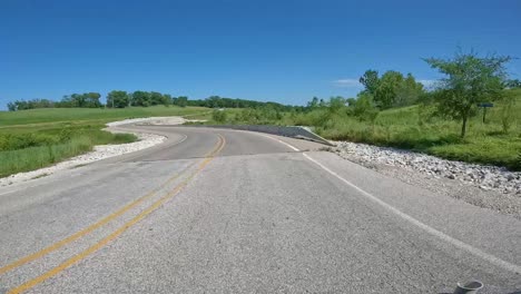 pov - driving on a secondary road with concrete barricades past wetlands and pastures in central iowa on a bright summer day