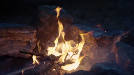 bonfire burning bright in slow motion, peaceful orange campfire with sparks surrounded by stones, close-up, 4k