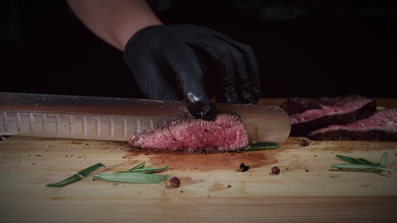 Chef cortando jugoso filete de solomillo con un cuchillo en una tabla de cortar de madera en la cocina, cámara lenta, primer plano