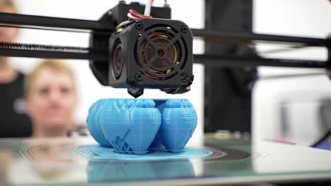 a close-up of a 3d printer in action creating intricate blue objects, showcasing the precision and technology behind modern additive manufacturing techniques