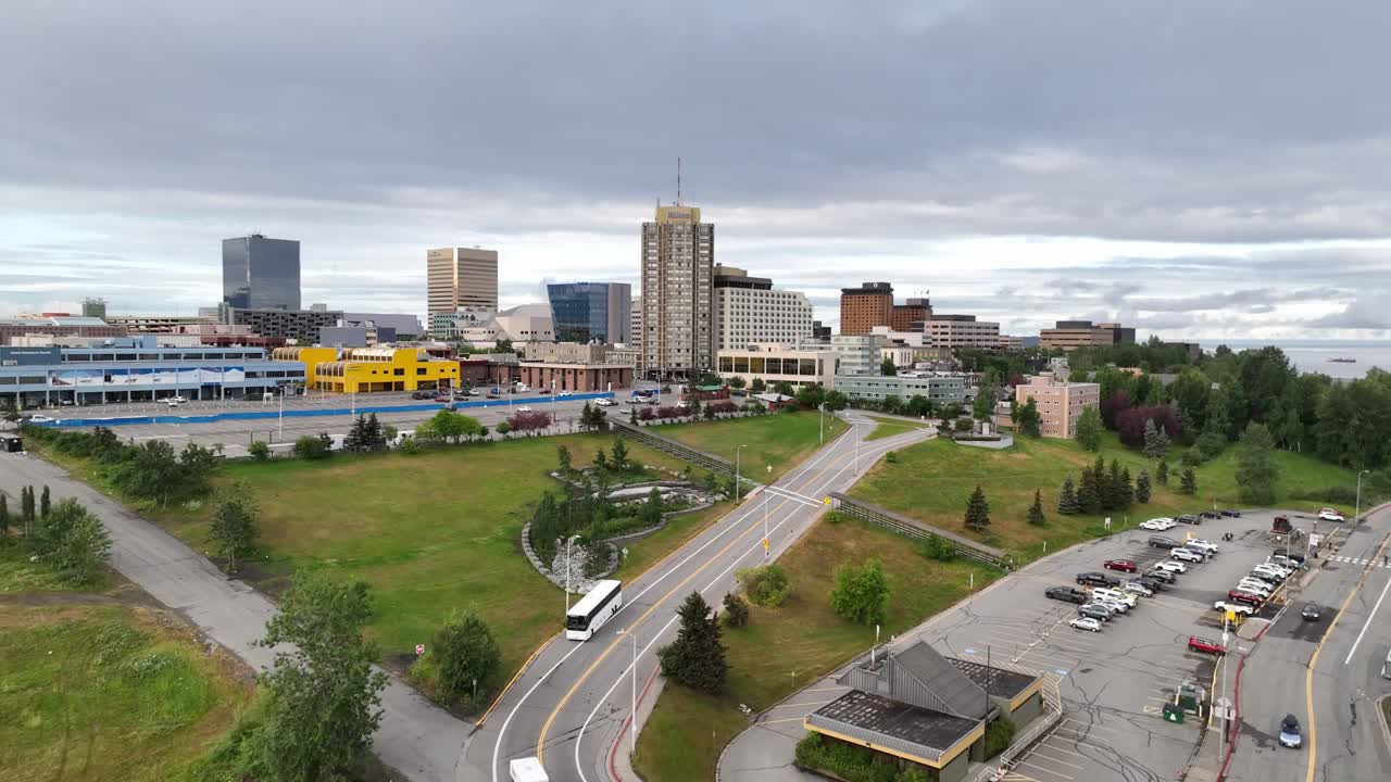 Aerial view of a city skyline with buildings, roads, and green spaces under a cloudy sky