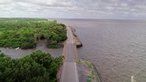 the drone flies over the road along the riverbank of punta lara, capturing the beautiful natural scenery on both sides.