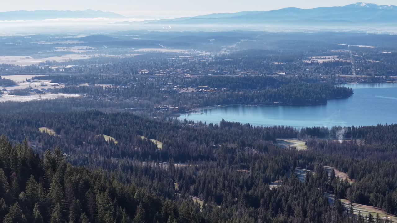 Vista aerea di una fitta pineta e un lago scintillante circondati da montagne vicino a Whitefish, Montana