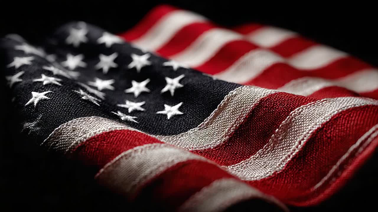 Et nærbillede af det amerikanske flag, der indfanger de rige teksturer og farver i dets ikoniske design i en dramatisk og stemningsfuld præsentation mod en mørk baggrund