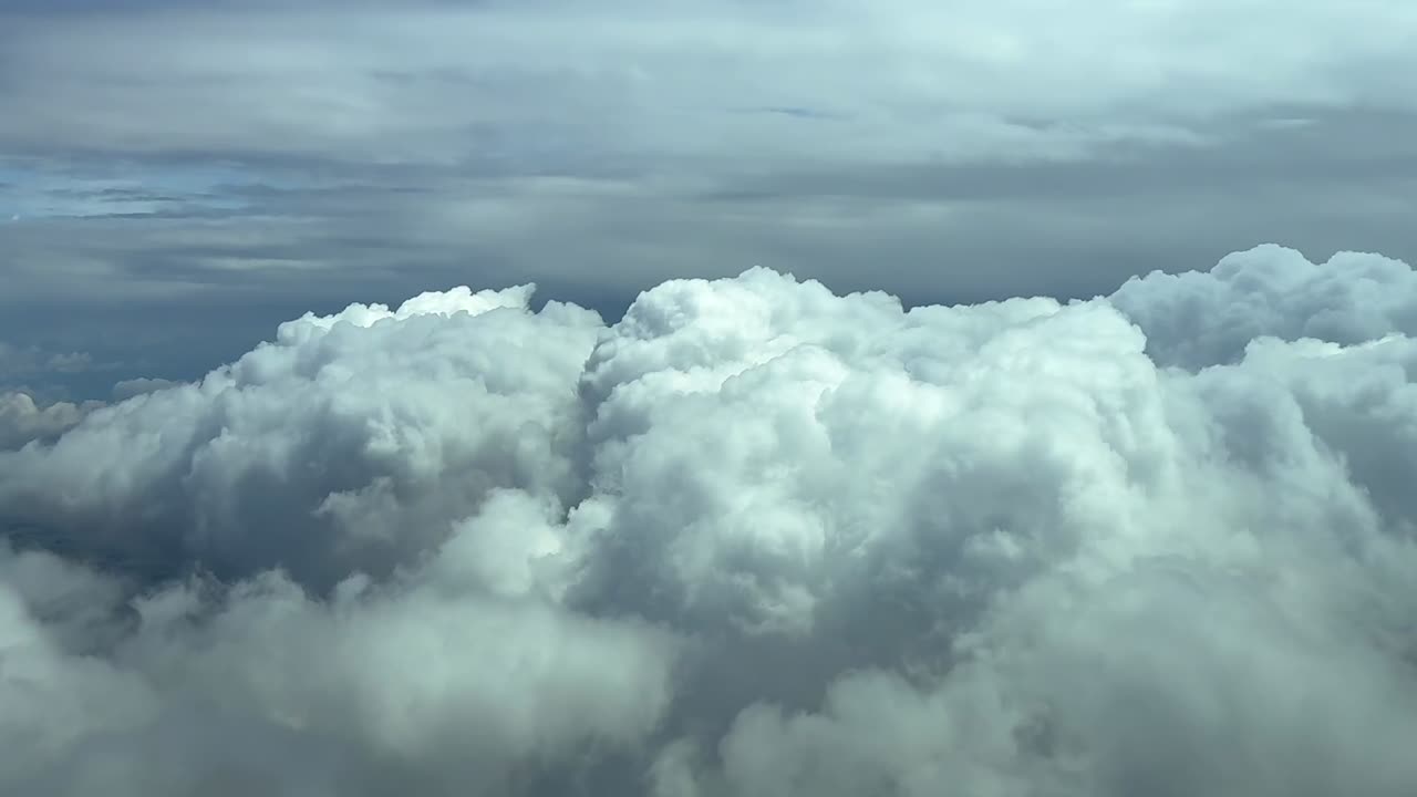 A peaceful cloudscape through the pilot’s eyes from cockpit while flying over some cottony white clouds