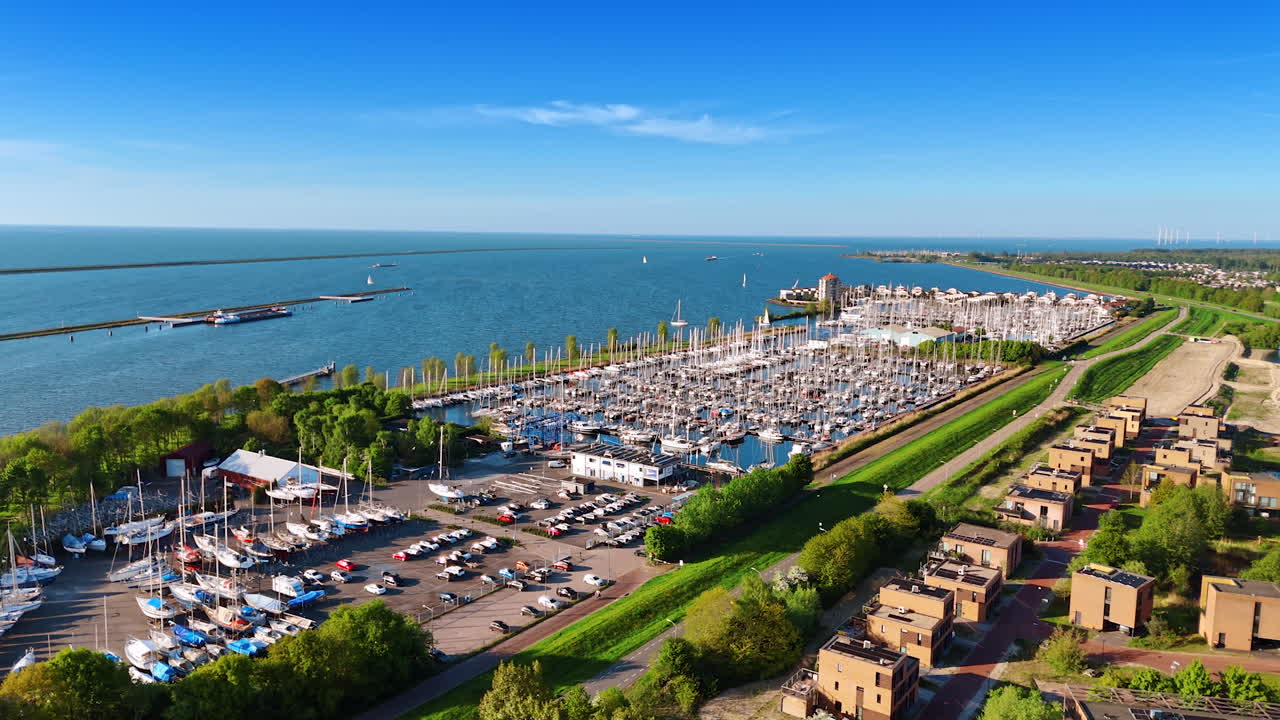 Parking lot with cars and yacht club with multiple boats on the anchor. Waterscape of lake Merkemeer with the dikes on at backdrop.
