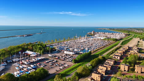 parking lot with cars and yacht club with multiple boats on the anchor. waterscape of lake merkemeer with the dikes on at backdrop.