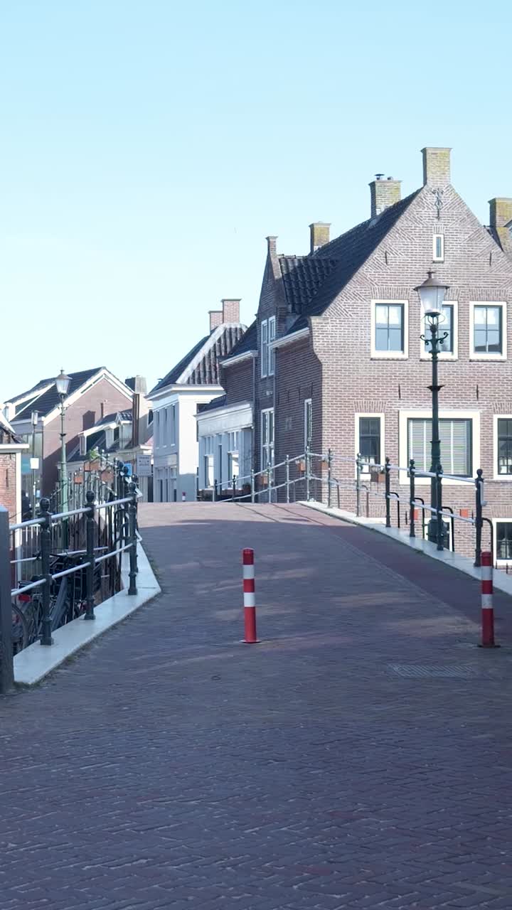 Rustige Europese dorpsstraat met historische bakstenen gebouwen en een fietser.