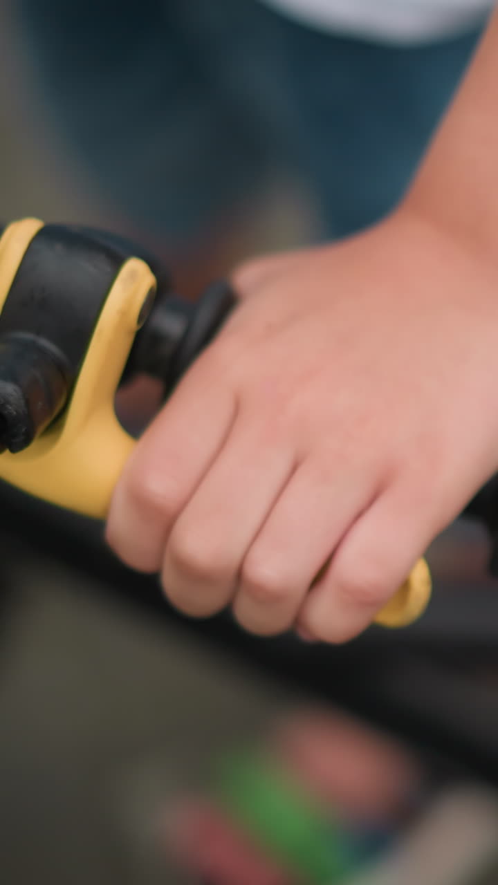 un primer plano de la mano de un niño agarrando firmemente la palanca de freno de una bicicleta, y descansando su mano en el manillar