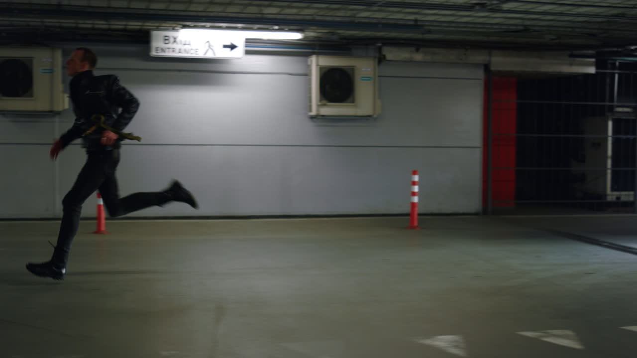 경찰 차에서 주차장에 달리는 자동 소총을 들고 있는 남성 테러리스트