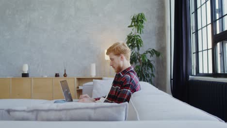 hombre trabajando en una computadora portátil en el sofá
