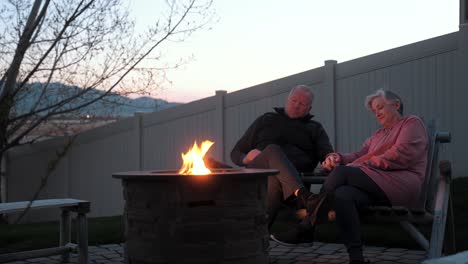 loving senior couple holding hands at a backyard fire pit