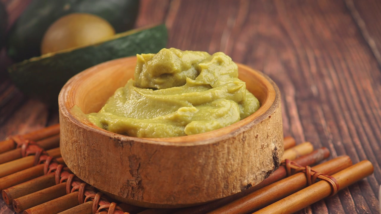 Fresh Guacamole in a Wooden Bowl on a Rustic Wooden Table