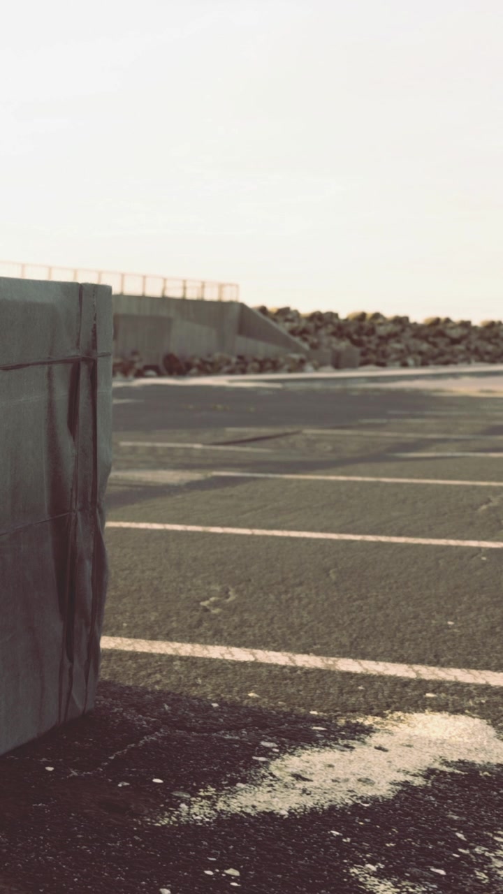 Concrete block rests on a parking lot near a coast during daylight hours