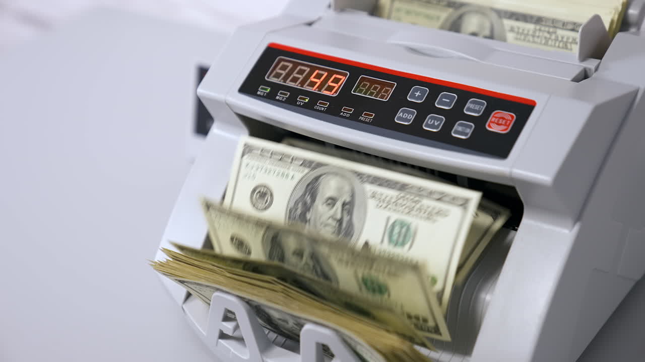 Attrezzatura contabanconote per il calcolo di denaro cartaceo. Una donna inserisce un pacco di banconote in dollari da contare. Meccanismo automatico per operazioni finanziarie bancarie.