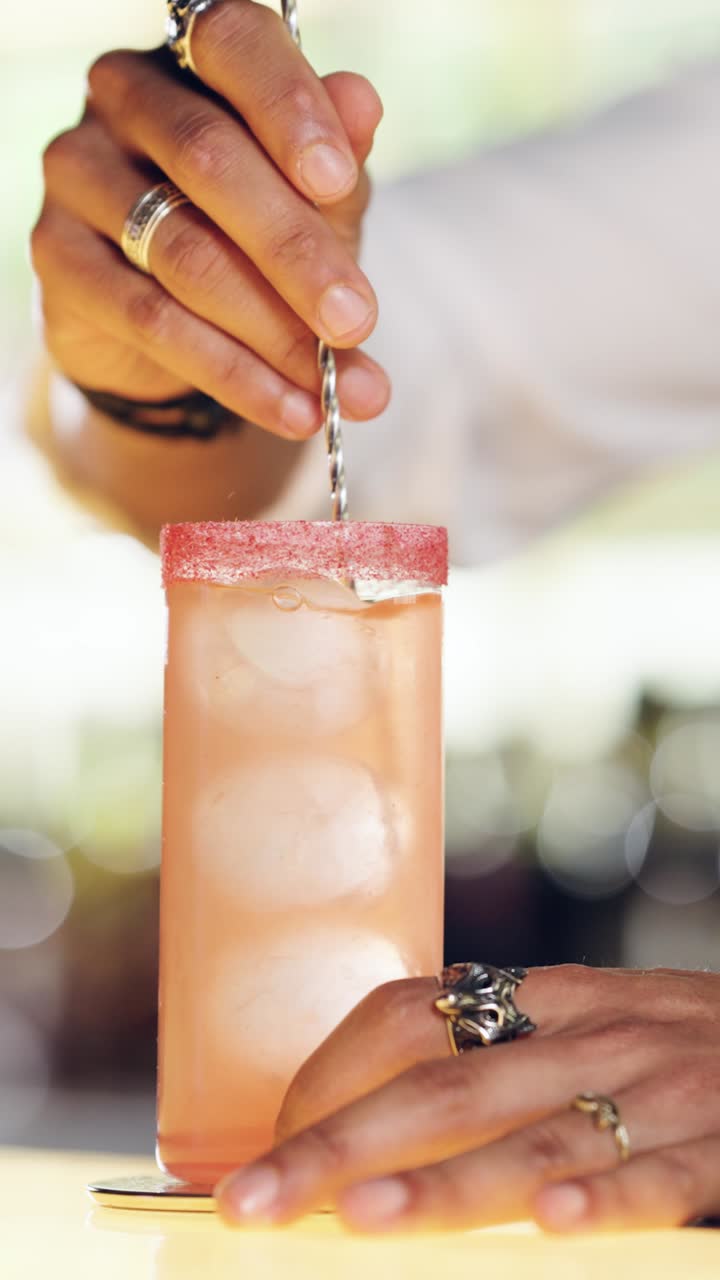 Barman che mescola un rinfrescante cocktail rosa con ghiaccio e bordo zuccherato