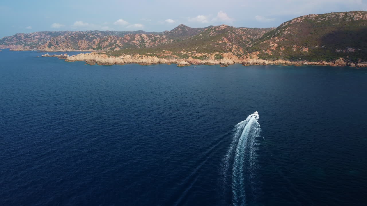 Aerial drone view of a motorboat speeding across the blue sea near the ...