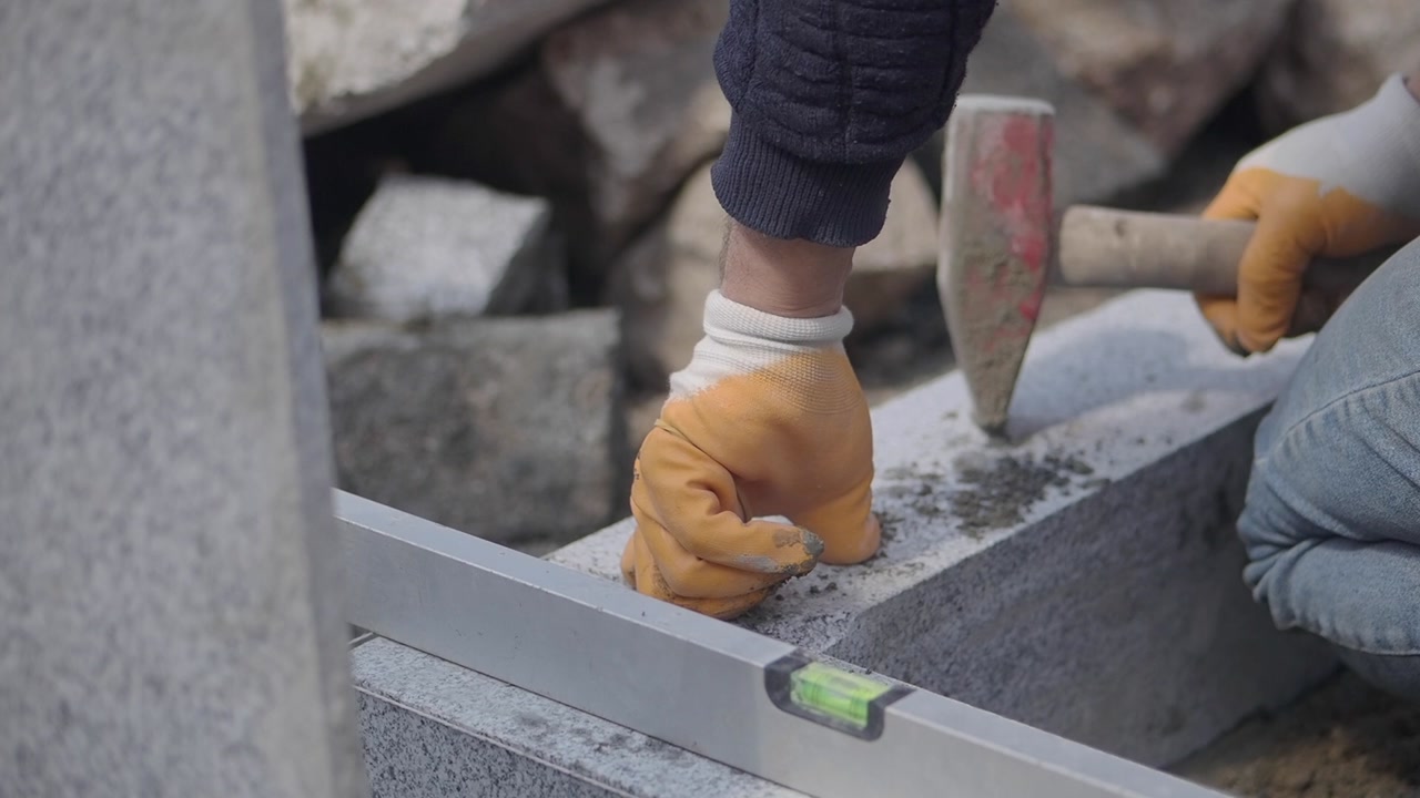 Construction Worker Laying Stone with Hammer and Spirit Level