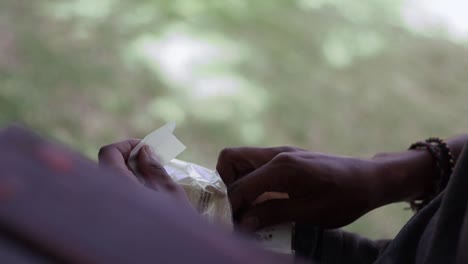 una toma a cámara lenta oh manos masculinas preparando tabaco para convertirlo en un cigarrillo