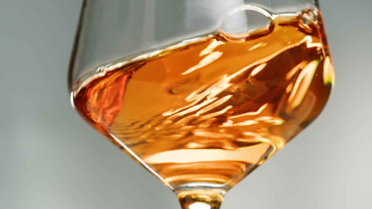 Rose Orange or white wine bottle and glass against a sunset in a peaceful vineyard, pouring of ecological natural wine. Cheers, hands with wine glasses, drinking alcohol.