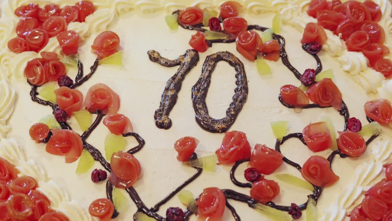 Torta fatta in casa con panna, decorata con rose e numero settanta di cioccolato