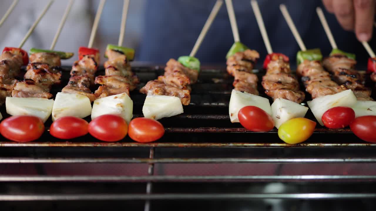 disparo de cerca de carne de cerdo a la parrilla y pollo en pinchos o kabab de pollo siendo asado en una parrilla de carbón ardiente por un vendedor de alimentos