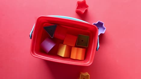 juguetes de plástico coloridos en un cubo rojo