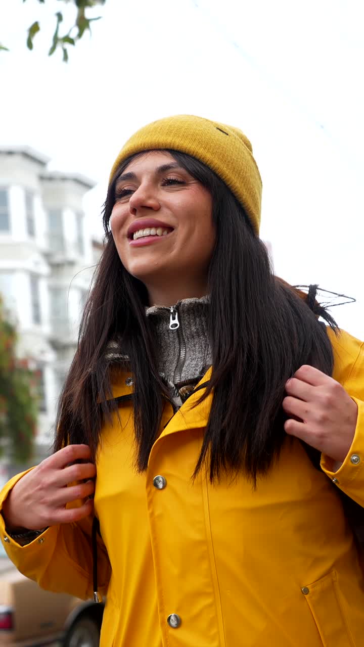 Giovane donna felice con un impermeabile giallo che sorride per strada