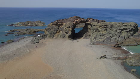 Fuerteventura-Island,-Ajui:-aerial-view-traveling-out-over-the-Jurado-arch-on-a-sunny-day-with-beautiful-colors