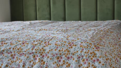 woman making the bed with floral sheets