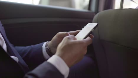 cropped shot of businessman using smartphone in car