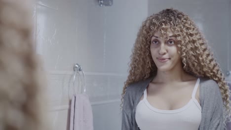 a woman with curly hair getting ready in front of a mirror