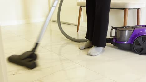 a woman vacuuming a tiled floor