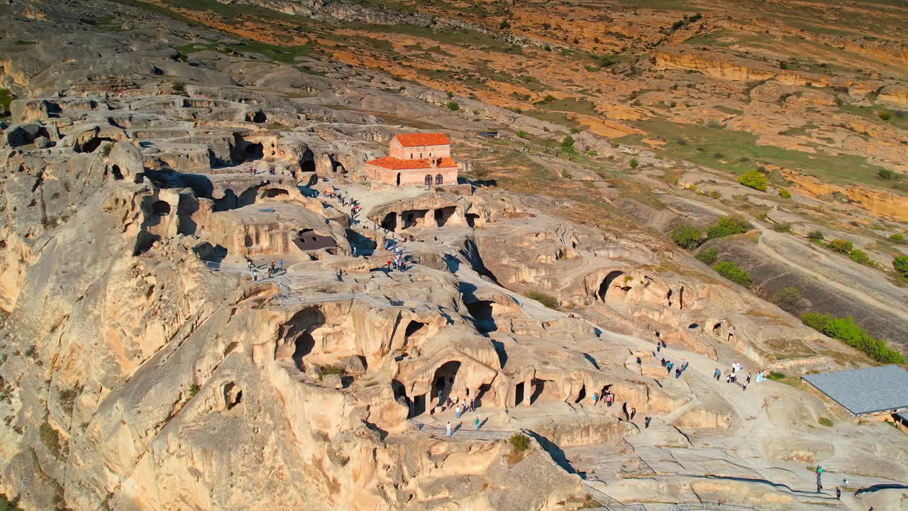 Pek çok turist kayalara oyulmuş eski evlerin yanından yürüyor. Gürcistan'ın ilk mağara şehirlerinden biri olan Uplistsikhe'ye havadan bakış.