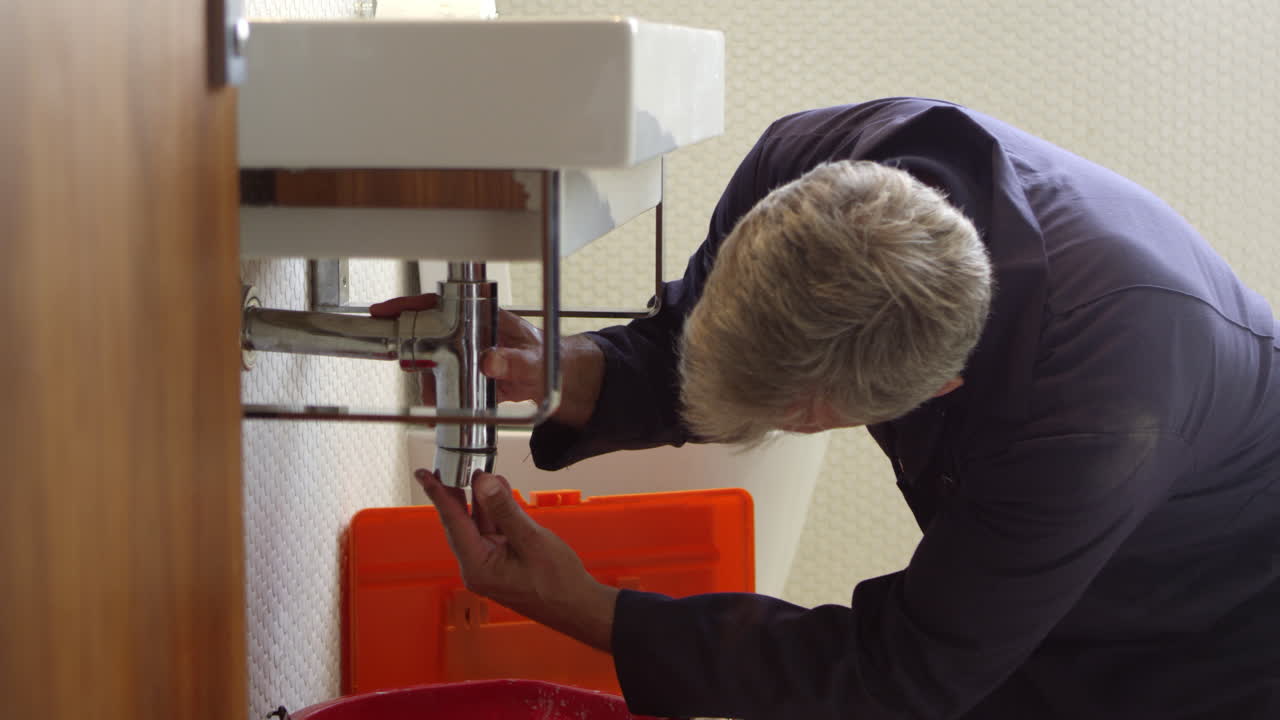 fontanero trabajando en el fregadero en el baño filmado en r3d