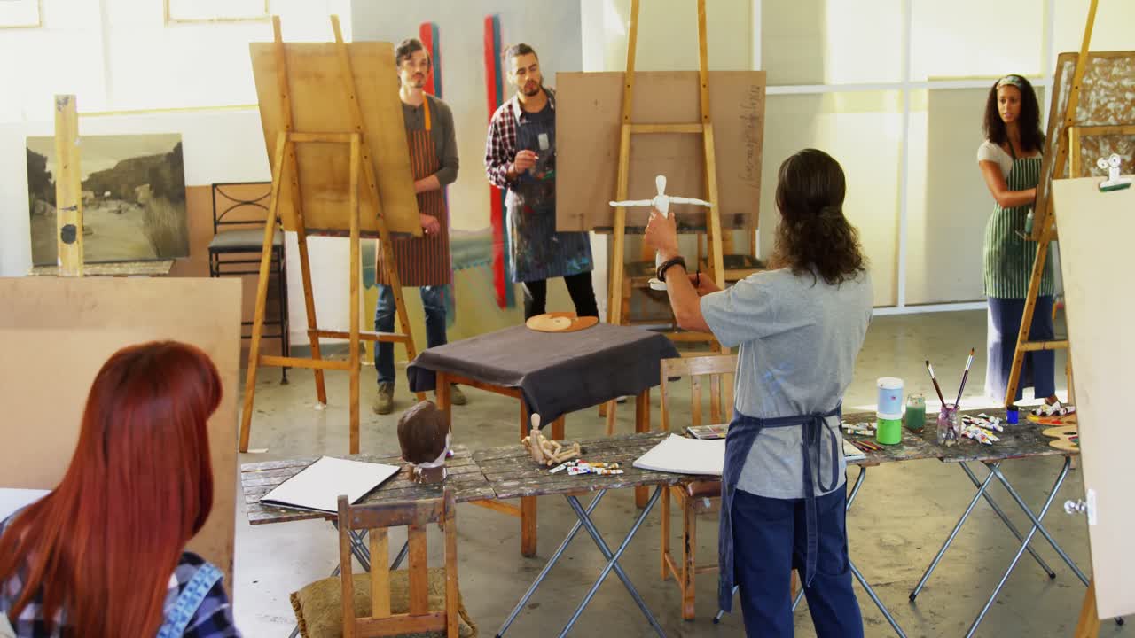 учитель держит статуэтку во время взаимодействия с художником 4k