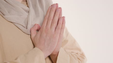 close up shot of hands of man wearing robes representing figure of jesus christ praying