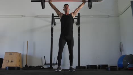 fit caucasian man training, exercising, lifting weights inside gym