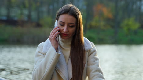 woman talking on phone in a park near a lake