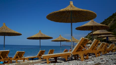 sunbeds and straw umbrellas on quiet beach with blue sea and sky background on vacation resort