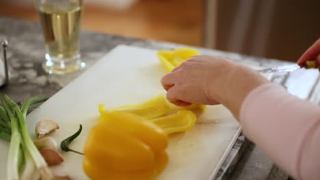 mujer preparando comida y cortando pimientos en tabla de cortar en cámara lenta