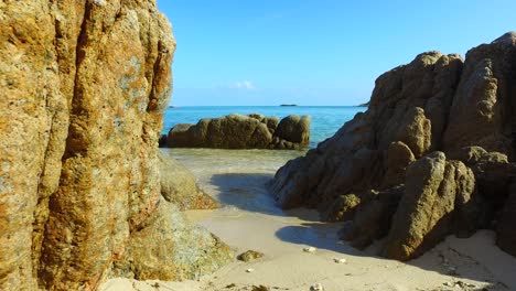 old limestone cliffs caved by ocean waves on white sand washed by calm clear sea water on blue sky background in vietnam