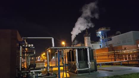 general shot at night in a chemical factory with starry sky and steam chimney releasing steam
