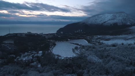ciudad de montaña nevada junto al mar al atardecer