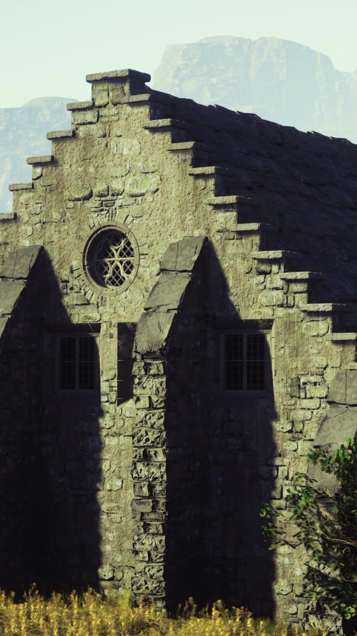 Antiguo edificio de piedra con ventana circular cerca de montañas a la luz del día.