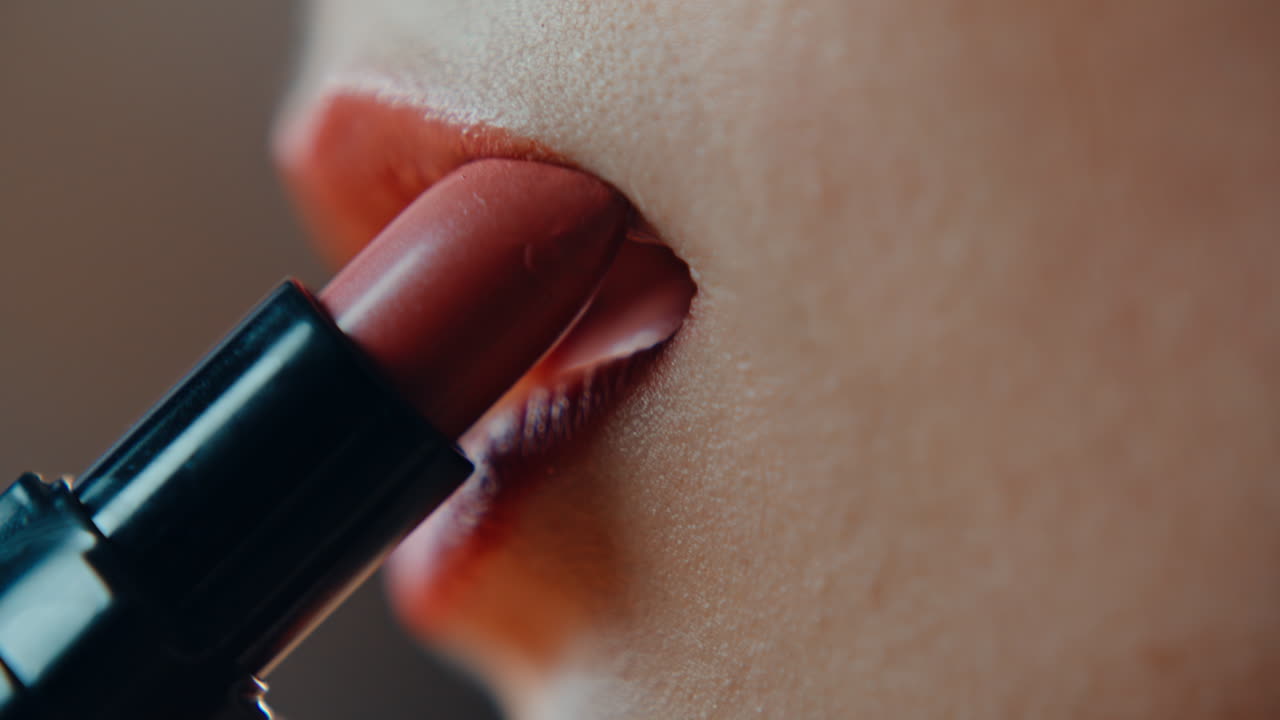 Closeup red lipstick painting woman lips. Lady applying red cosmetics
