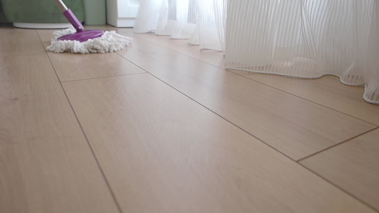Mopper et lyst tregulv med en lilla mopp