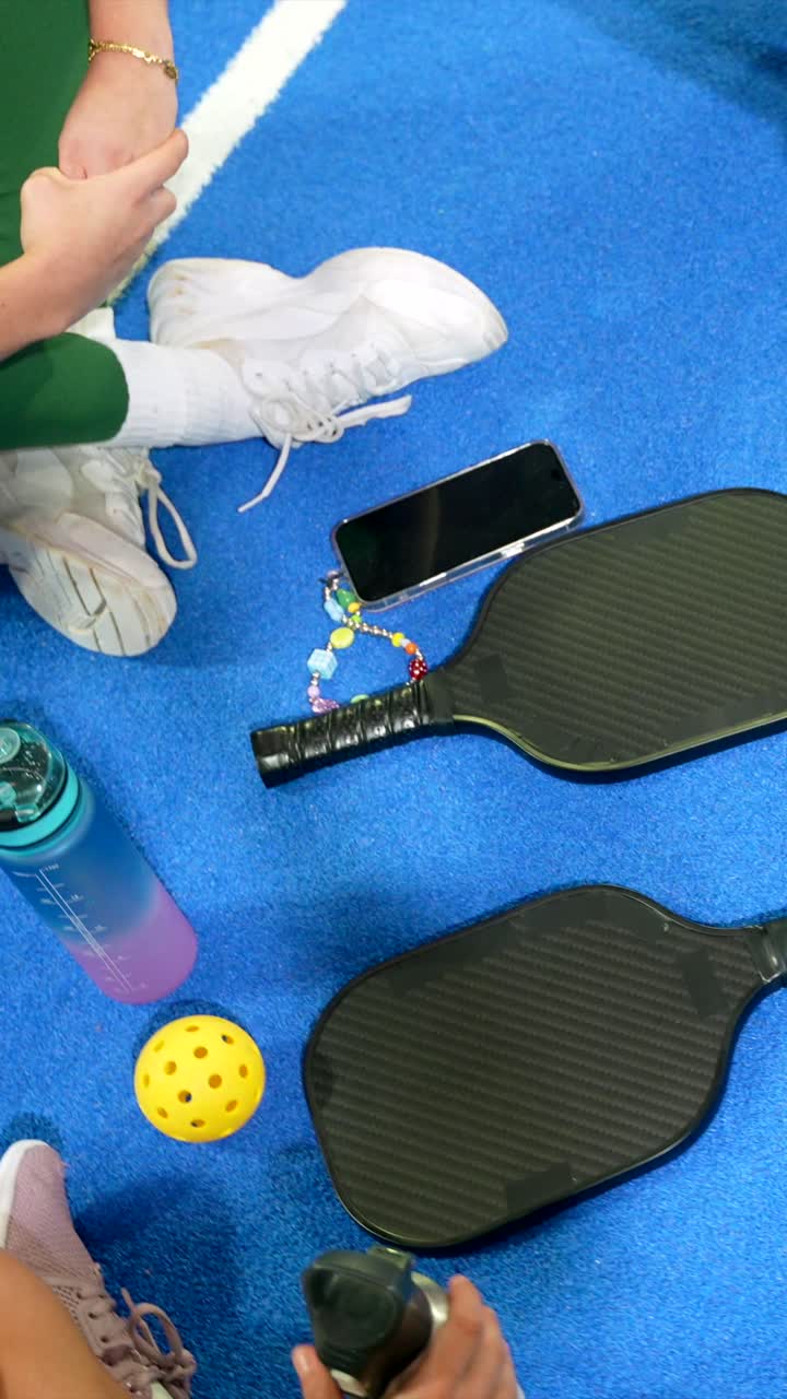 Vista aérea de jogadores de pickleball descansando em uma quadra azul.