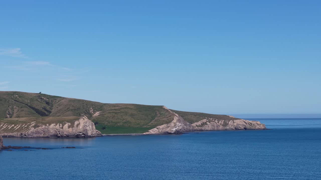 Zoomed in view of volcanic peninsula folding into beautiful inky-blue ocean from Birdlings Flat Beach (Banks Peninsula South, New Zealand)